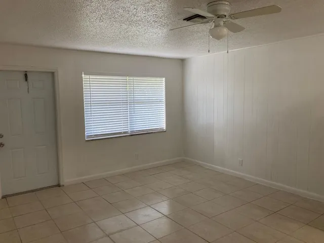 an empty room with windows and fan