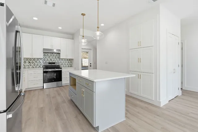 a kitchen with kitchen island white cabinets and stainless steel appliances