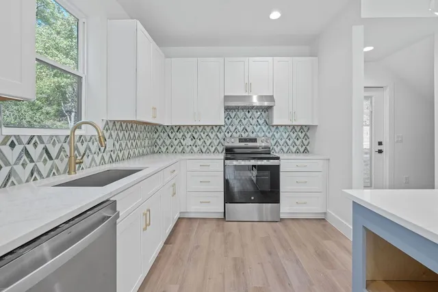 a kitchen with kitchen island white cabinets and stainless steel appliances