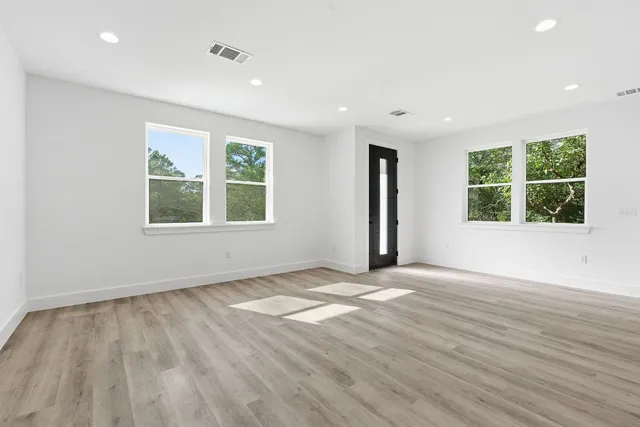 an empty room with wooden floor and windows