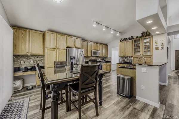 a kitchen with stainless steel appliances kitchen island granite countertop a table chairs sink and cabinets