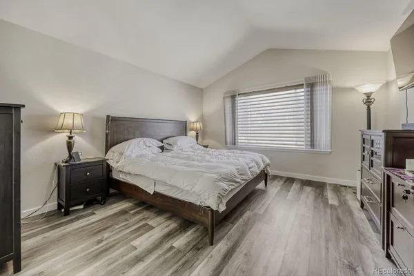 a bedroom with a bed a tv and wooden floor