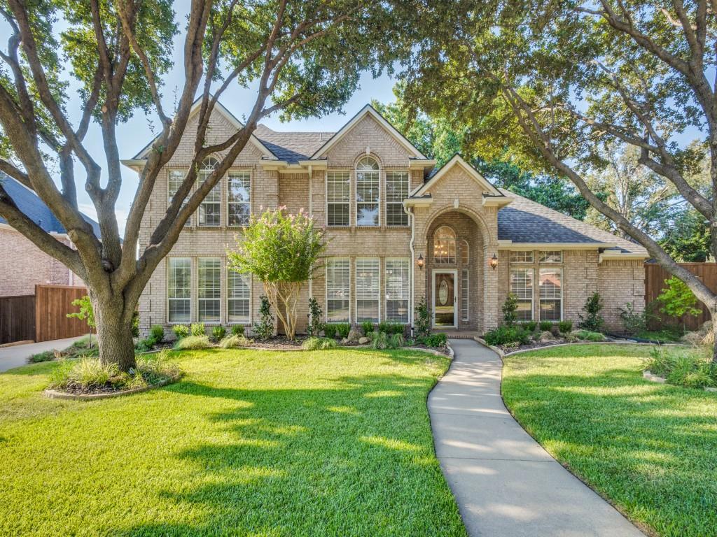 a front view of a house with a garden and trees