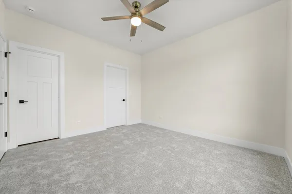 an empty room with windows and ceiling fan