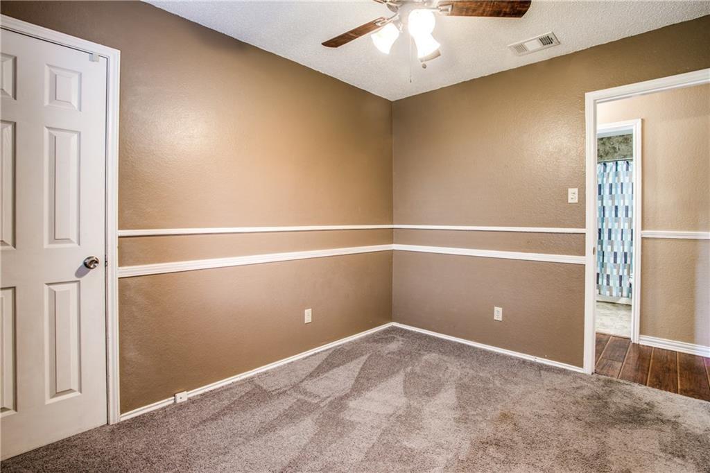 6817 Haltom Road Fort Worth, TX 76137 - Photo 8 of 25 Bedroom featuring neutral-toned walls with chair rail molding, carpet flooring, a ceiling fan, and a paneled door