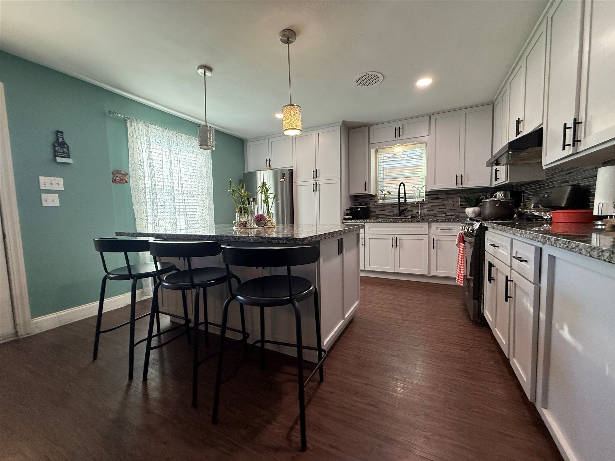 8823 Shadow Crest Street Houston, TX 77074 - Photo 11 of 14 a kitchen with stainless steel appliances granite countertop wooden floor a stove a sink dishwasher a microwave oven and a dining table with wooden floor