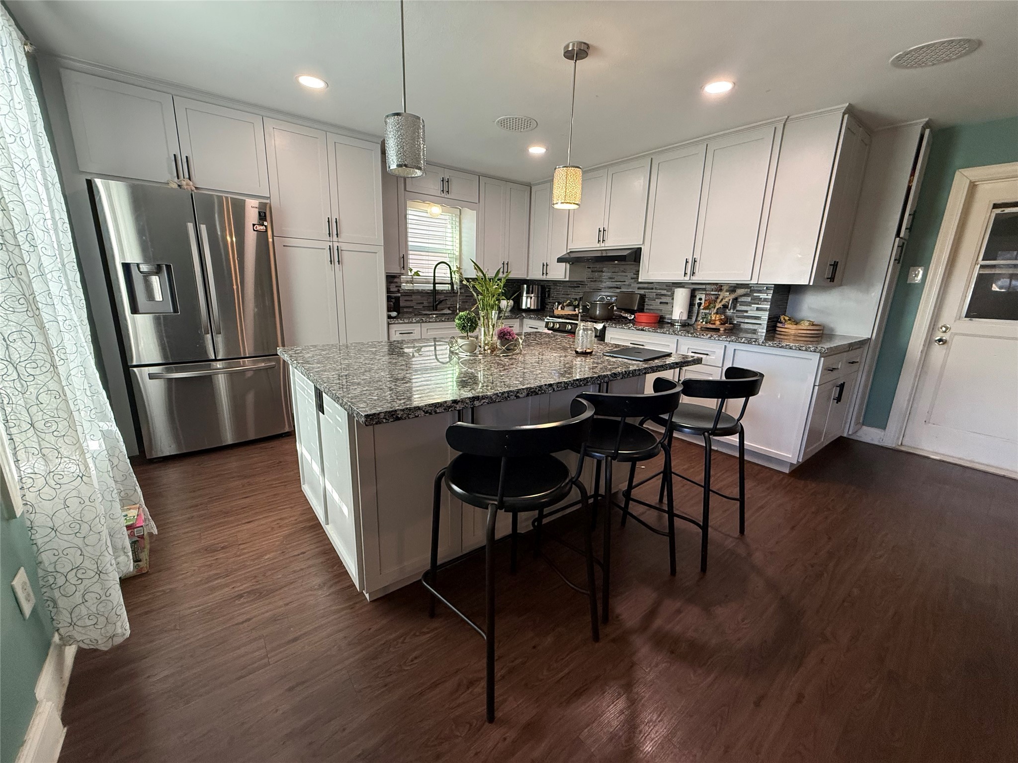 8823 Shadow Crest Street Houston, TX 77074 - Photo 2 of 14 a kitchen with stainless steel appliances a dining table chairs refrigerator and microwave