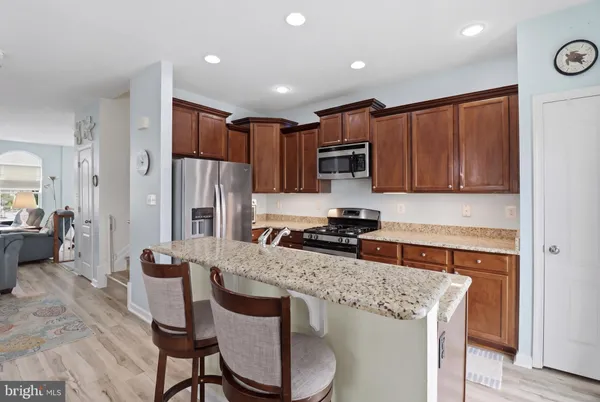 a kitchen with stainless steel appliances granite countertop a refrigerator a stove and a sink with wooden cabinets