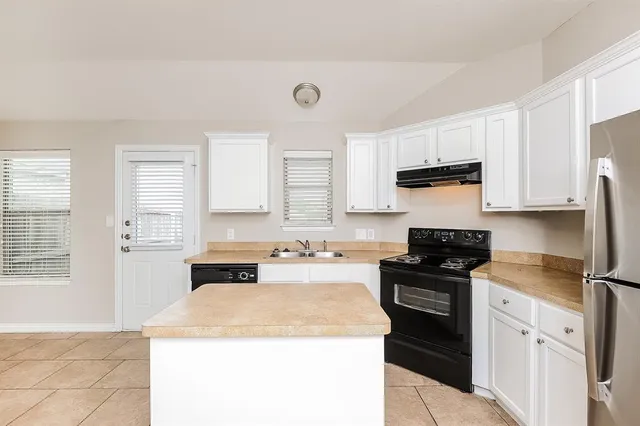a kitchen with a refrigerator a stove top oven and cabinets