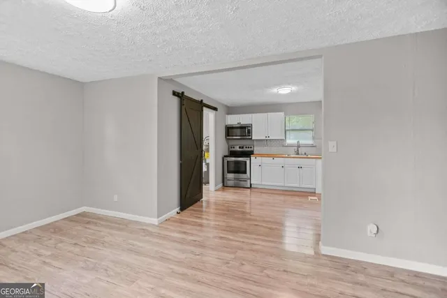 a view of a kitchen with wooden floor electronic appliances and cabinets