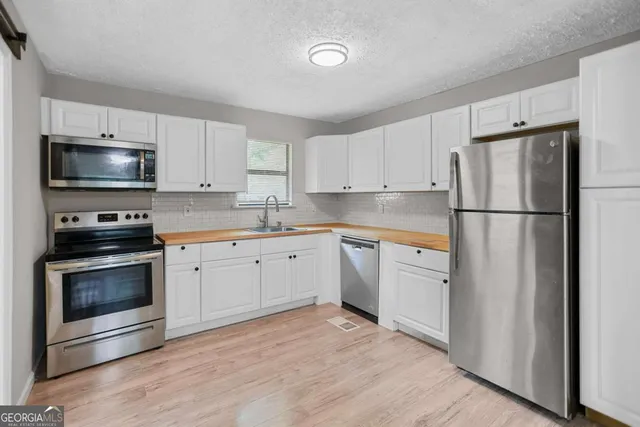 a kitchen with granite countertop white cabinets and stainless steel appliances