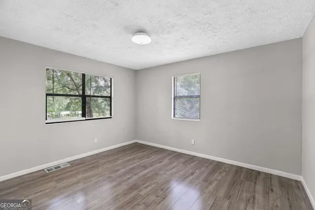 an empty room with wooden floor and window