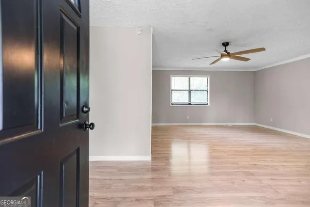 an empty room with windows and fan