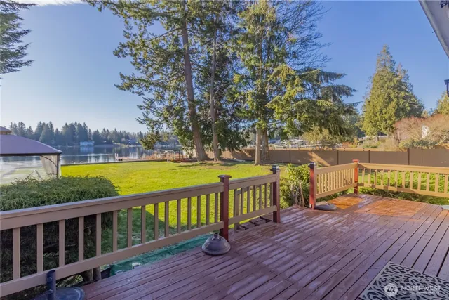 a view of a deck with wooden floor and fence next to a yard