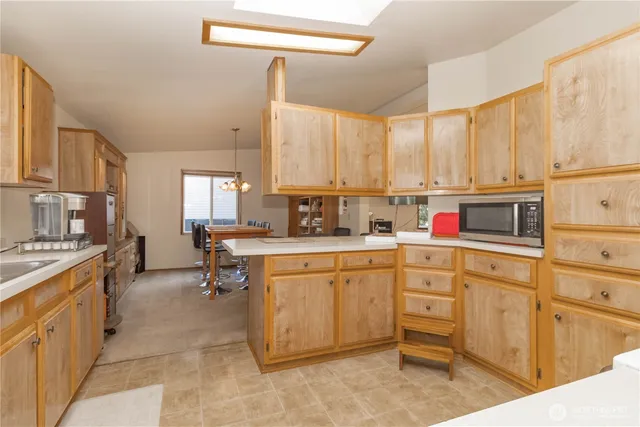 a kitchen with kitchen island granite countertop a sink counter top space appliances and cabinets