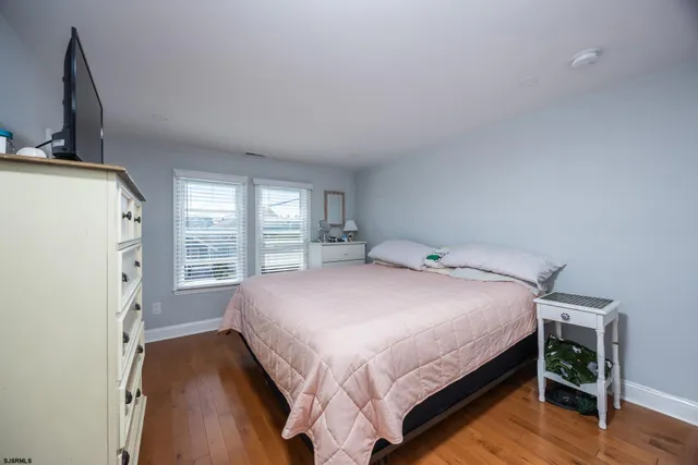 a bedroom with a bed next to a large window with wooden floor