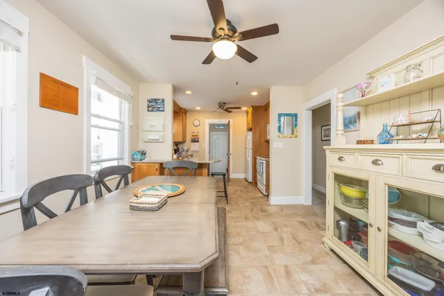 a view of a dining room and livingroom with furniture wooden floor a rug a fireplace and a chandelier