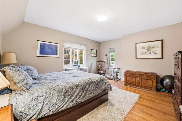 a bedroom with a bed and dresser with wooden floor