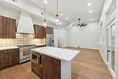 a large kitchen with a large refrigerator a sink dishwasher a oven and a kitchen island with wooden floor