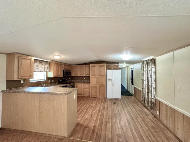 a kitchen with stainless steel appliances a refrigerator a sink dishwasher a stove top oven a counter space and cabinets