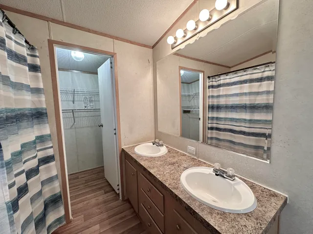 a bathroom with a granite countertop sink a mirror and a shower