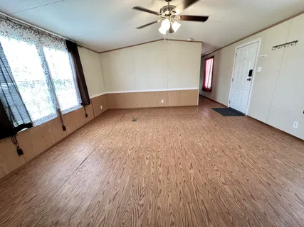 an empty room with wooden floor fan and windows