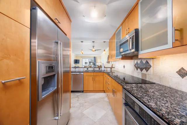 a large kitchen with stainless steel appliances granite countertop a large counter top a stove and a refrigerator