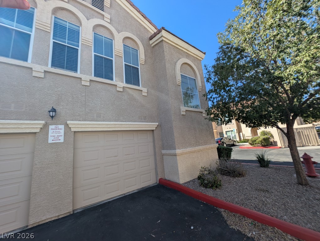 10550 West Alexander Road, Unit 2117 Las Vegas, NV 89129 - Photo 2 of 24 Arched windows and clean stucco siding elevate this exterior under a clear blue sky.