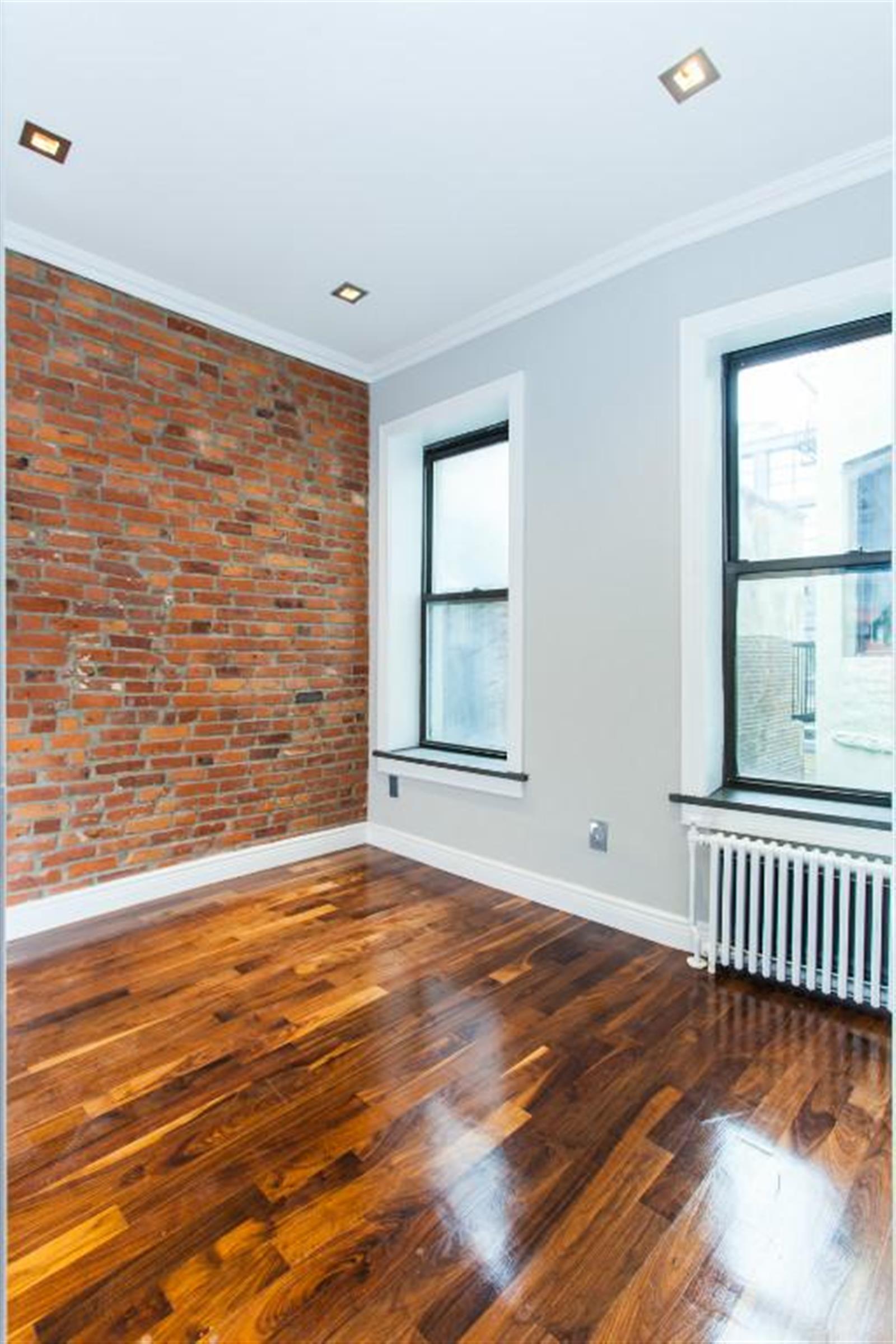 232 Elizabeth Street, Unit 5B Manhattan, NY 10012 - Photo 2 of 5 a view of an empty room with wooden floor and a window
