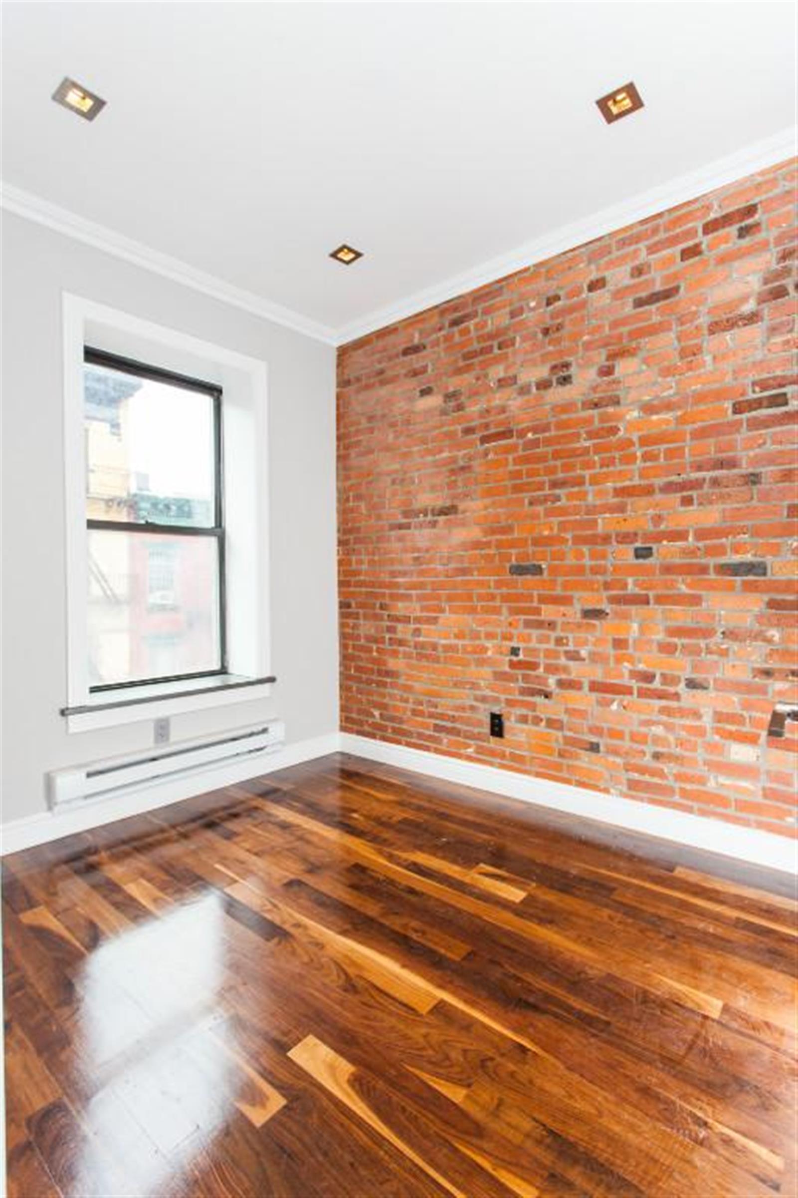 232 Elizabeth Street, Unit 5B Manhattan, NY 10012 - Photo 4 of 5 a view of an empty room with wooden floor and a window