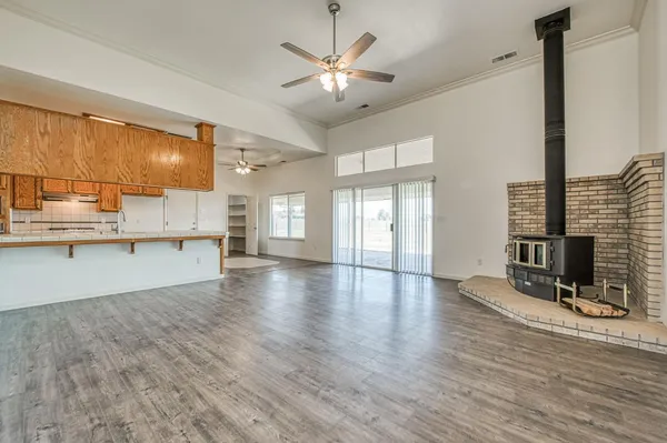 an empty room with wooden floor chandelier fan and windows
