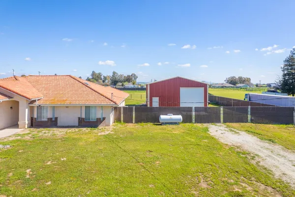 a view of a lake with lawn chairs and large trees