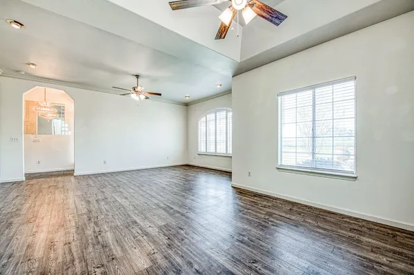 a view of empty room with wooden floor and fan