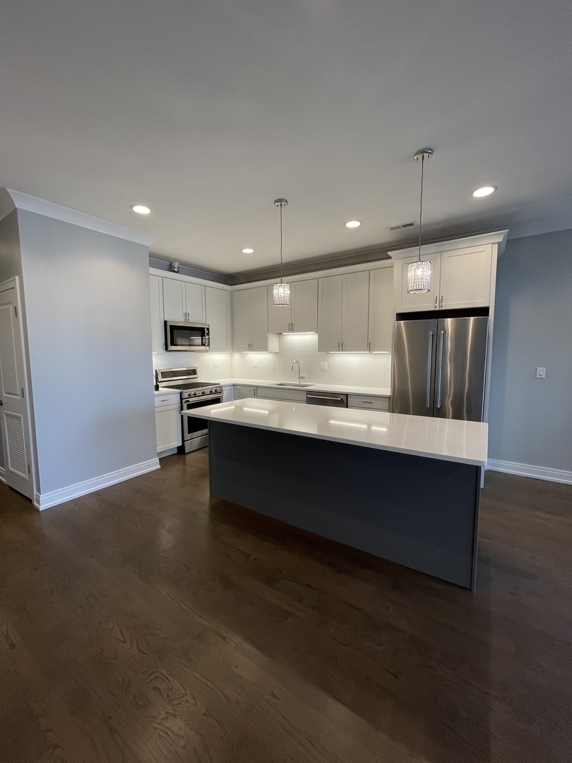 2036 West 18th Street, Unit 4 Chicago, IL 60608 - Photo 4 of 29 a large kitchen with kitchen island a sink stainless steel appliances and cabinets