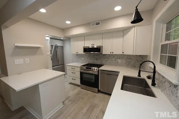 a kitchen that has a sink a stove and chairs