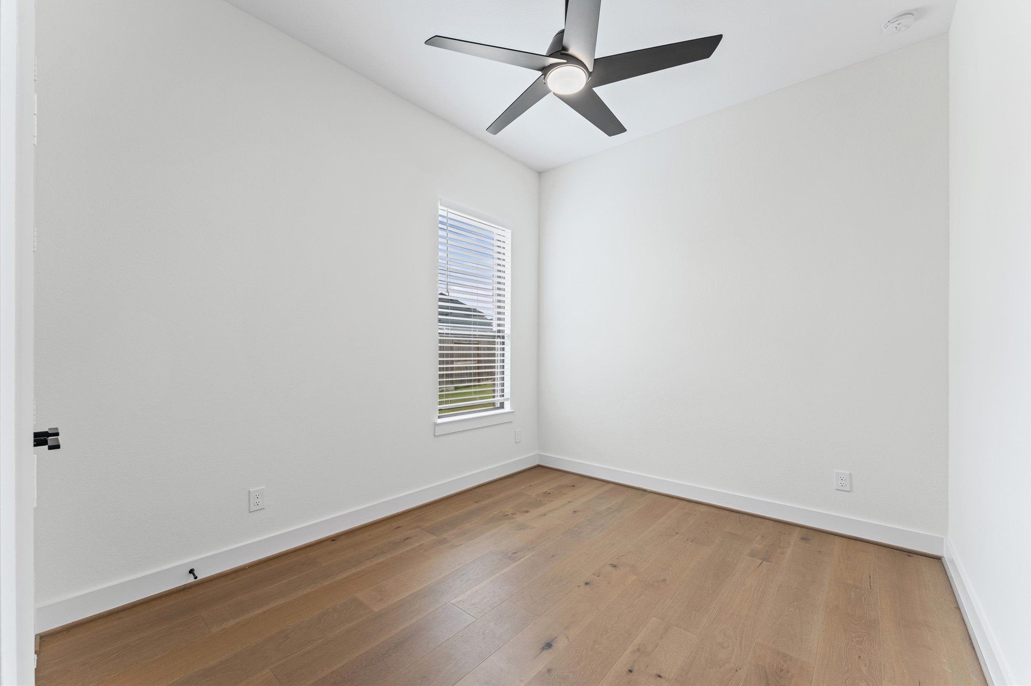 7327 Trial Rdg Drive Fulshear, TX 77441 - Photo 11 of 24 Spacious secondary bedroom with hardwood-look flooring, ceiling fan, and a clean neutral palette — ready for your vision.
