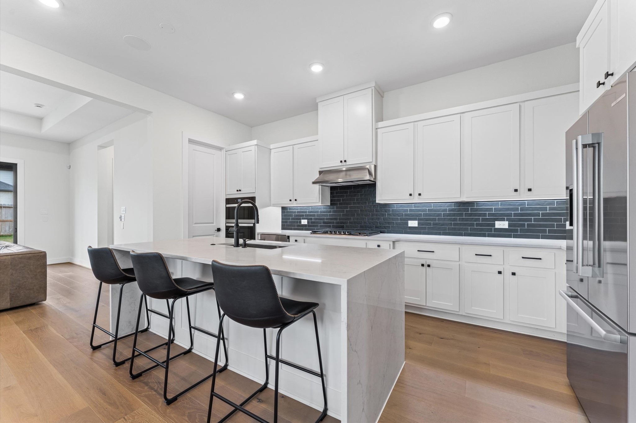 7327 Trial Rdg Drive Fulshear, TX 77441 - Photo 3 of 24 The island anchors the kitchen with comfortable seating — a natural spot for morning coffee, casual meals, or conversation while dinner's on.