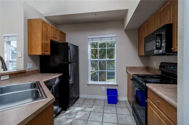 a kitchen that has a sink wooden cabinets and a stove top oven