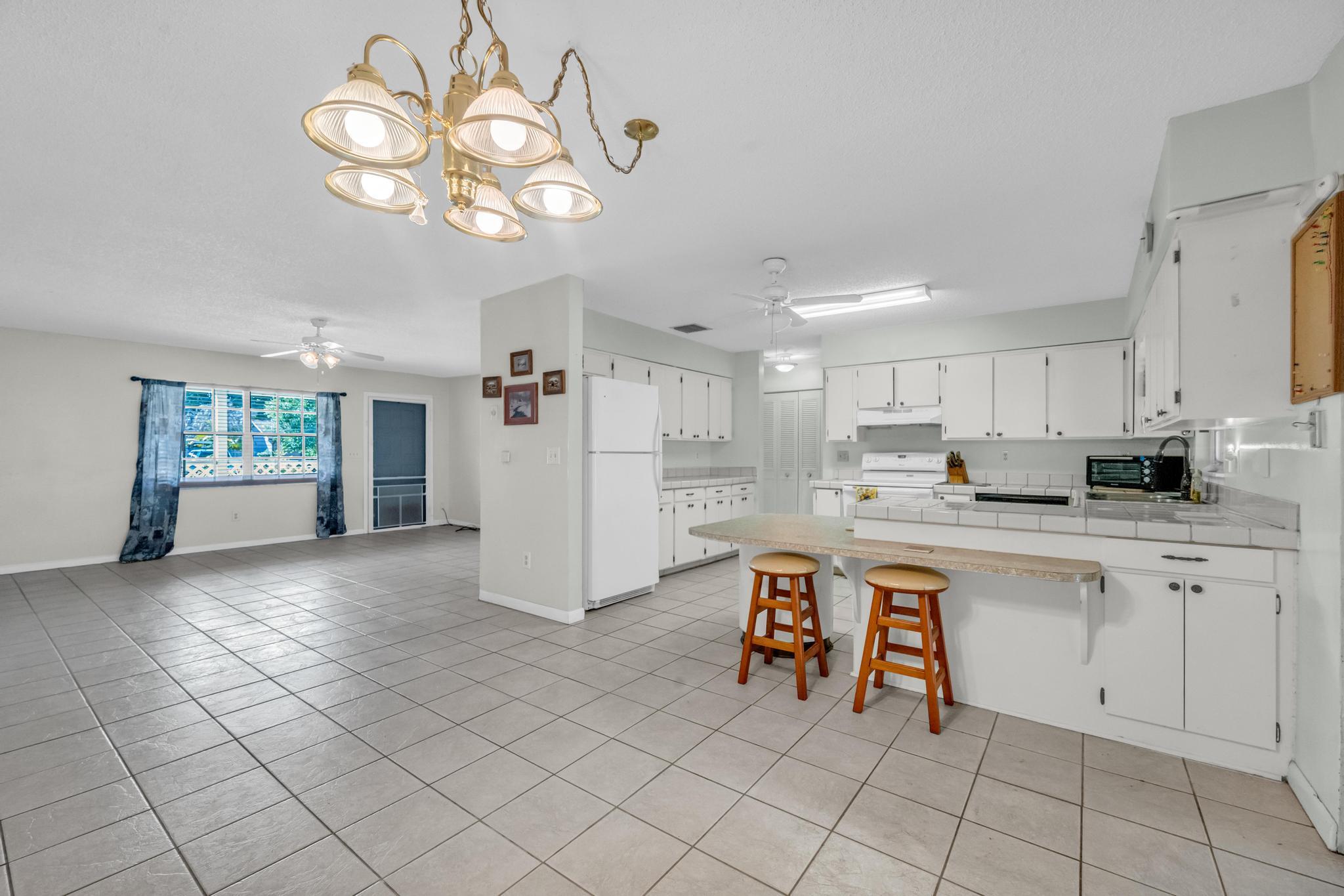 5406 Sunset Boulevard Fort Pierce, FL 34982 - Photo 5 of 33 a large white kitchen with white cabinets and chandelier