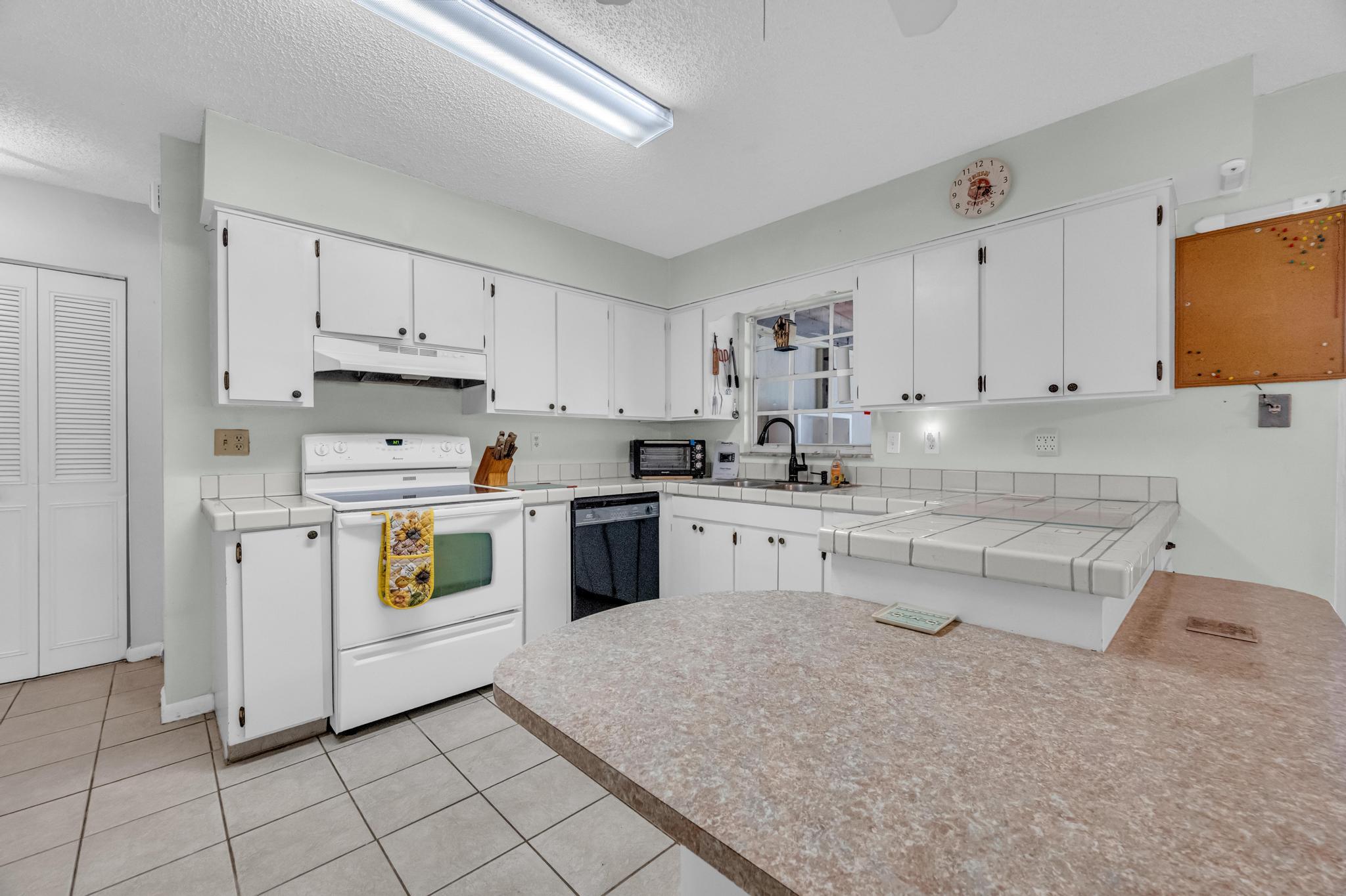 5406 Sunset Boulevard Fort Pierce, FL 34982 - Photo 7 of 33 a kitchen with white cabinets and white appliances