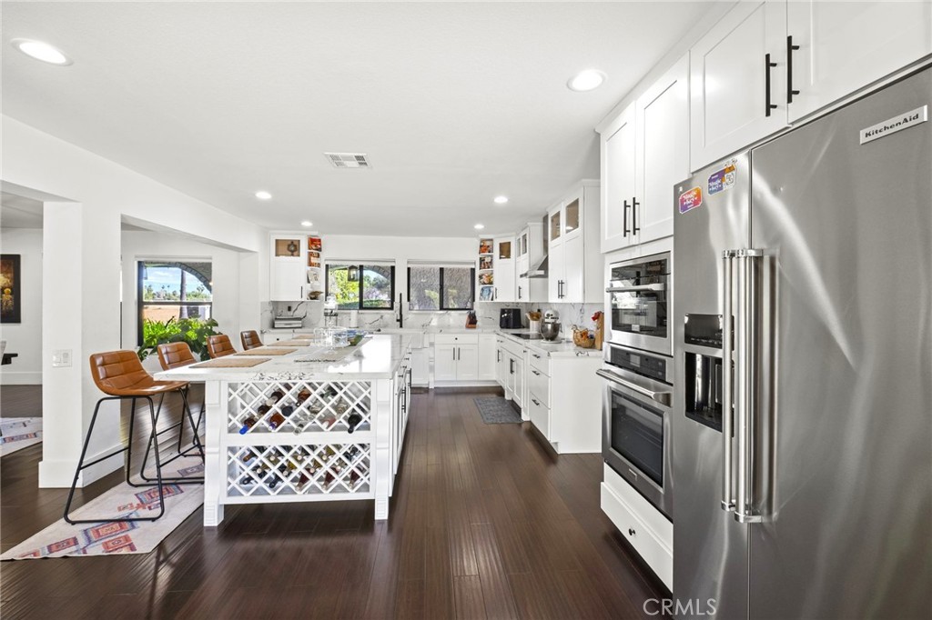 7710 Broadacre Place Riverside, CA 92504 - Photo 16 of 65 a kitchen with stainless steel appliances kitchen island granite countertop a refrigerator oven a sink dishwasher and white cabinets with wooden floor