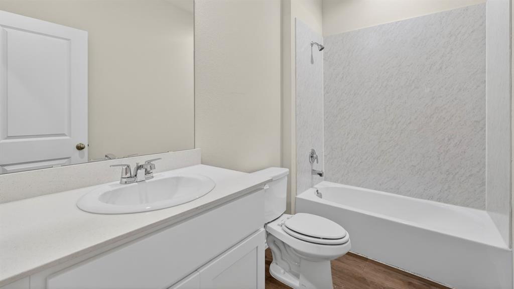 1683 Mantle Road Crandall, TX 75114 - Photo 27 of 31 Bathroom featuring a white vanity with an integrated sink, polished chrome faucet, a large wall-mounted mirror, a standard toilet, and a bathtub with a shower and patterned surround