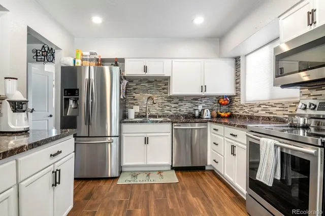 a kitchen with granite countertop a refrigerator stove and sink