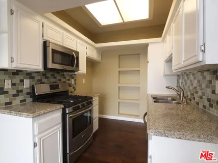 a kitchen with granite countertop a sink a stove and microwave