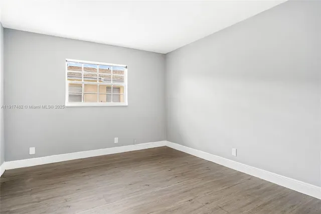 an empty room with wooden floor and window