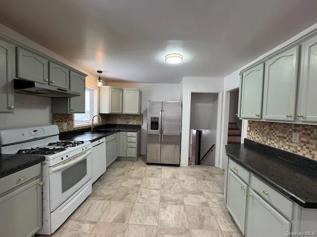 a kitchen with stainless steel appliances granite countertop a stove a sink and a refrigerator