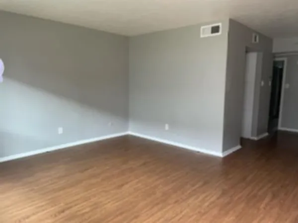 a view of an empty room with wooden floor and closet