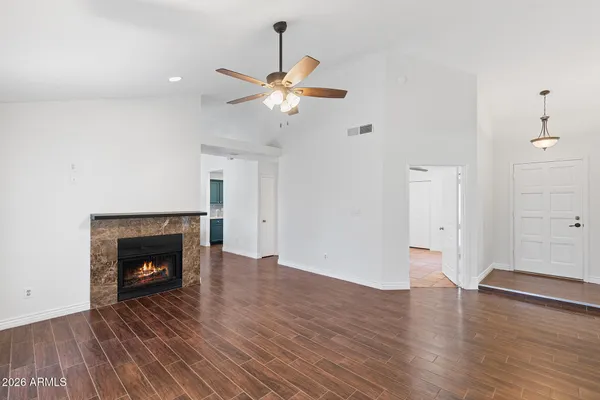 a view of an empty room with wooden floor and a fireplace