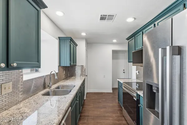 a kitchen with stainless steel appliances granite countertop a sink stove and refrigerator