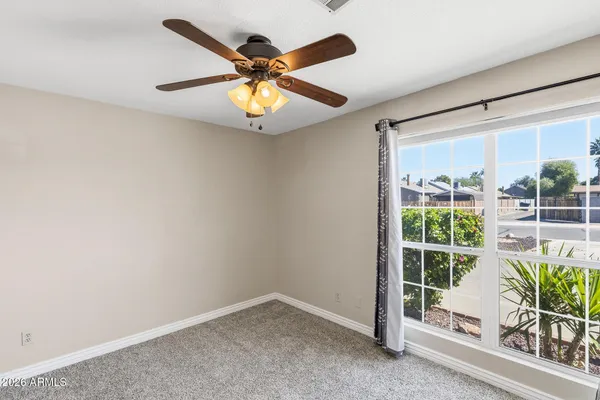 an empty room with a window and ceiling fan